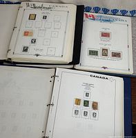 Three open binders showing mounted Canadian stamps