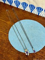 Both necklaces laid flat to show full length and pendant designs