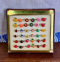 Front view of display showing 25 colourful enamel rings and “Fashion Finger Rings” label