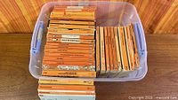 Plastic bin holding roughly 45 orange-spine Penguin paperbacks
