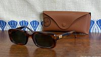 Front angled view of sunglasses with case behind