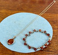 Necklace and bracelet laid side by side on blue circle showing overall design