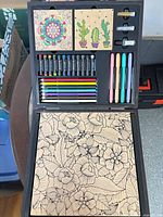 Open wood case showing all contents: pencils, pastels, markers, panels, glitter vials