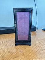 Front view of rectangular black metal votive holder with purple glass panel and latch door