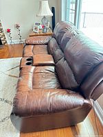 Front angled view showing full brown leather loveseat, console, cushions and armrests