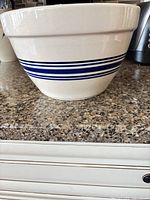 Side view of cream ceramic bowl with blue stripes