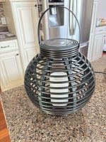 Full view of bronze spherical lantern with handle and interior LED pillar