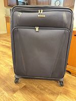 Front view of navy Samsonite soft-sided spinner suitcase showing front pocket, zipper pulls and four wheels