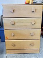 Front view showing four drawers with square pulls and light finish