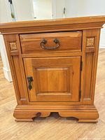 Front view showing drawer, cabinet door, hardware, carved details, base style