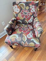 Front view of floral fabric accent chair with wood legs
