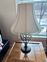 Full view of lamp on table showing shade, bead trim, and metal base