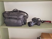 Camera body with lens and camera bag on shelf