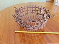 Full view of wrought iron lattice basket with grapevine details next to measuring tape for scale