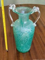 Full view of green mottled glass vase with clear loop handles and measuring tape showing height