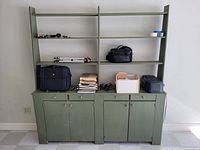 front view of green stepback cupboard showing shelves, drawers, doors and surface wear