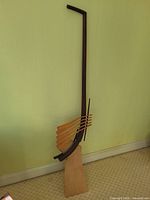 full view of tall rosewood and maple staff sculpture leaning against wall