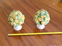 Pair of glazed ceramic lemon tree topiaries beside measuring tape
