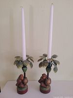 Full view of both monkey palm candleholders with taper candles inserted