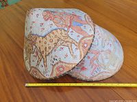 Two conical hand-painted Thai straw hats on table with measuring tape