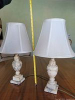 Both alabaster lamps with shades standing on table beside tape measure for scale
