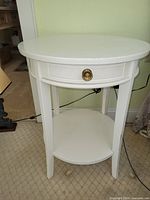 White round nightstand showing drawer with brass-tone knob and lower shelf