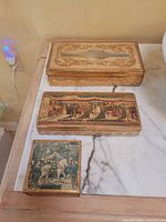 All three gilded Florentine boxes displayed on marble surface