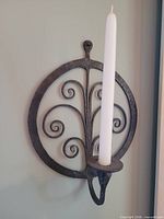 Single wrought iron scroll wall sconce holding a taper candle