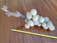 Full view of alabaster grape cluster sculpture with measuring tape for scale