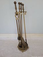 Full view of brass fireplace tool set showing four tools on stand