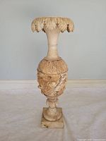 Full view of carved alabaster pedestal urn showing leaf rim, tapered neck, relief body, and square base