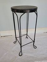 Full view of stool showing iron base, twisted legs, wood seat