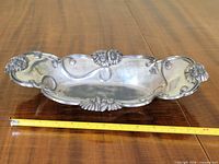 Entire silver plated floral rim bowl on table with tape measure for scale