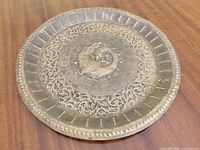 Top view of brass tray showing peacock engraving, scroll border, beaded rim