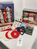 Overall view of lot showing crackers, ornament set, candles, felt coasters, wrapping paper, star dish and additional items
