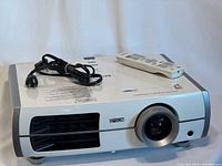 Front view of Epson 6100 projector with remote and power cord placed on top