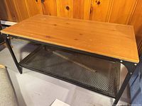 Angled view of table showing wood top and mesh shelf
