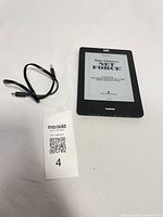 Front view of Kobo Touch eReader displaying ebook page with USB cable