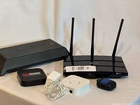 All five electronic items arranged together: Slingbox, TP-Link router, Red Rhino box, Philips Hue Bridge with cable, Apple AirPods charging case