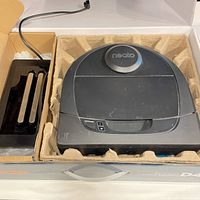 Top view of Neato Botvac D4 in molded packaging alongside dock