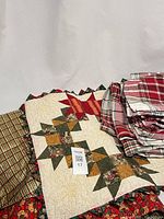 Stacked view showing small quilt, plaid textiles and part of tree skirt