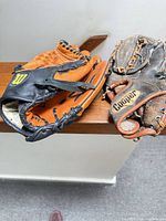 Two baseball gloves side by side on railing
