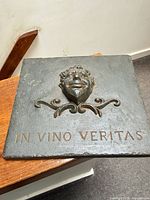 Front view of cast iron plaque with face, scroll detail, and text