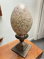 Full view of speckled egg on ornate metal stand