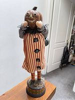 Front view of pumpkin-head figurine showing dress, face, base