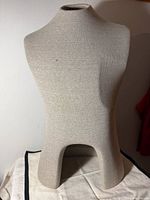Front view of beige fabric-covered male torso mannequin bust on tabletop