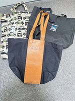 Three tote bags laid out: MoMA canvas/leather, Harrods car print, Columbia Icefield black tote
