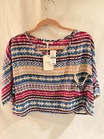 Front view of Millau sheer cropped top on hanger, tags visible