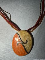 close-up of enamel pendant showing swirl design and strand materials