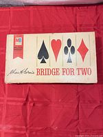 Closed tan box top displaying suits and branding